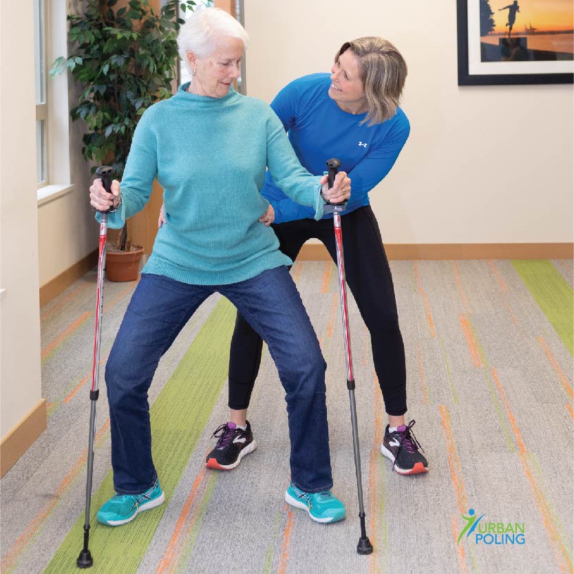 elder woman being assisted by another woman on using activator poles for exercise from AskSAMIE