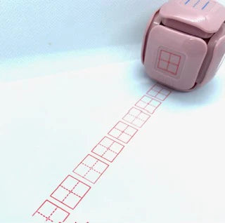 LegiLiner LegiCube Self-Inking Teacher Stamp - Math and Handwriting Lines Multi-Roller Stamp stamping red box of square quarters angled view in white sheet from AskSAMIE