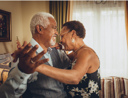 Elderly couple dancing together in a warm, homey setting aging in place.