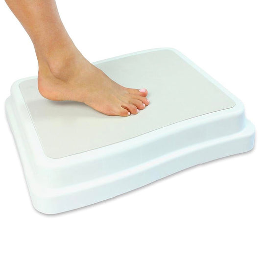 Bare foot stepping onto the white bed step, a wide platform that adds 4 inches of height for getting into a tall bed.
