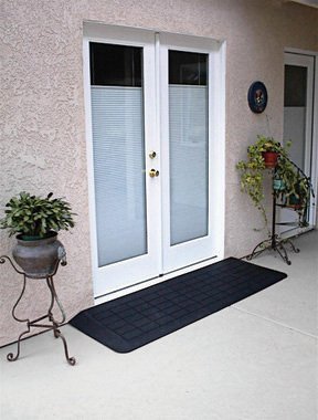 Rubber threshold ramp in place at a set of white French patio doors, giving step free access from a stucco patio into the house.