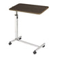 Angled view of the height adjustable overbed table with a chrome steel column and walnut top that rolls over a hospital bed for meals