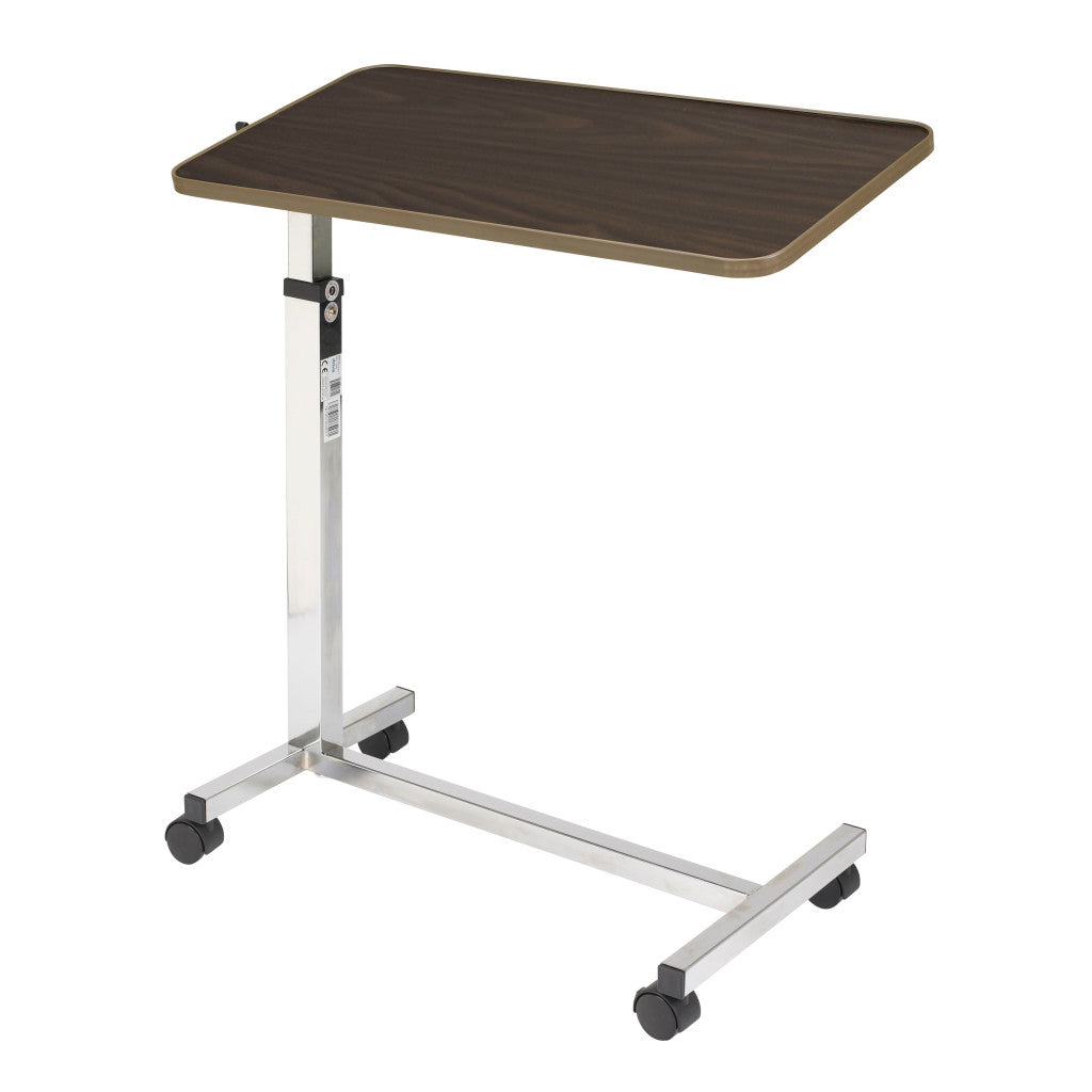Angled view of the height adjustable overbed table with a chrome steel column and walnut top that rolls over a hospital bed for meals