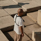 Man shown standing outside with concrete block in front of him, he has glasses and Are device strapped to his upper body.