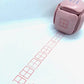 LegiLiner LegiCube Self-Inking Teacher Stamp - Math and Handwriting Lines Multi-Roller Stamp stamping red box of square quarters angled view in white sheet from AskSAMIE