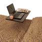 Overbed table positioned over a bed holding a laptop, newspaper, and drink so a person on bed rest can work and eat without getting up.