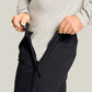 Man in a gray shirt pulling open the waist-to-ankle side zipper of black pants at the hip