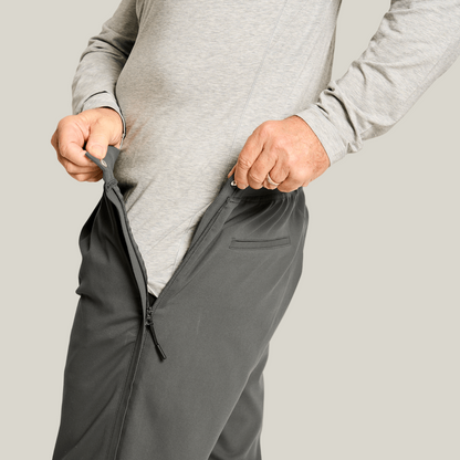 Side view of a man wearing heathered slate grey side-zip pants with white sneakers, hand in pocket