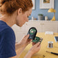Person using an ocularX round LED hand magnifier to see small parts on a circuit board during a hobby project.
