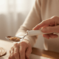 Close-up of a hand holding the swivel spoon's wide white handle, the pivoting stainless bowl keeping oatmeal level