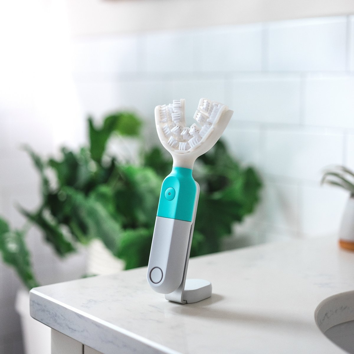 SymplBrush automatic toothbrush on its magnetic charging stand, showing the U shaped bristle cradle that cleans every tooth at once.
