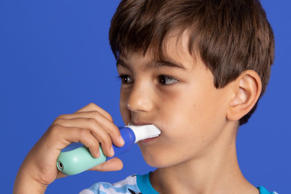 A young boy brushing independently with SymplBrush Jr., holding the handle with a full fist instead of a pencil grip.